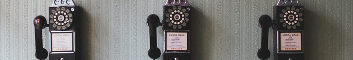 photograph of three telephones on a wall